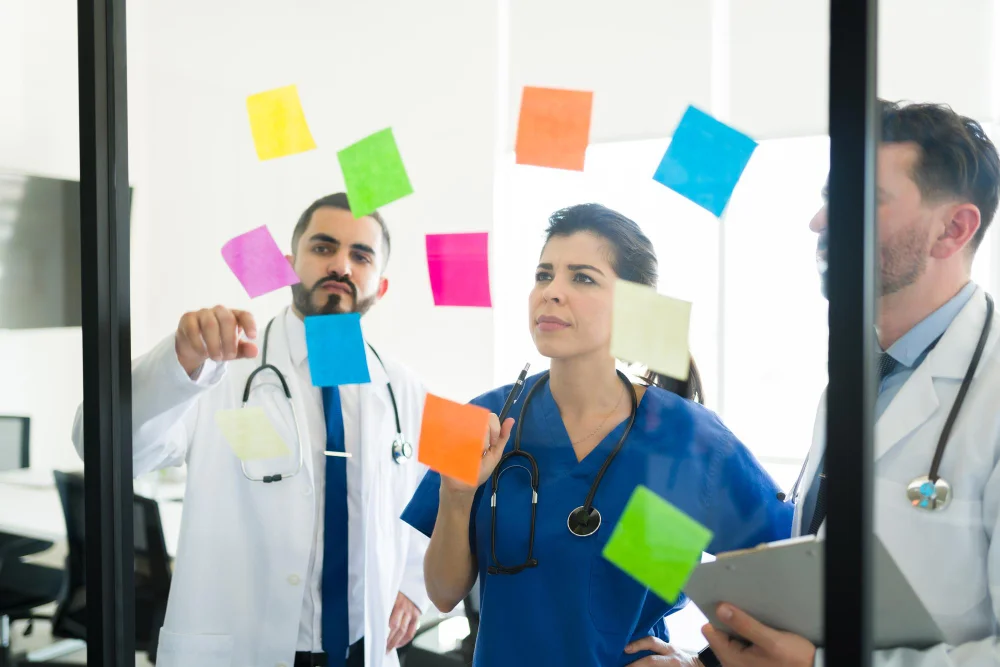 Nurses and medical professionals discussing strategies on a glass board with sticky notes, representing confidence building and focused preparation for the NCLEX exam.